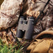 The grey FRONTIER ED X 8X42 binoculars carried by a hunter using a carry strap